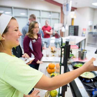 A young female student is being handed an omelette at a dining station at Springfield College