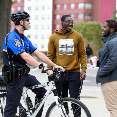 An officer on a bicycle has a discussion with two students